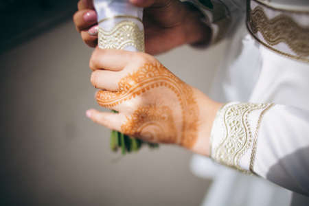 Bridal bouquet, hold the wedding bouquet in your hand, satin ribbons adorn the wedding bouquet of roses, on the background of the bride's dress, fresh flowers, made by a floristの写真素材