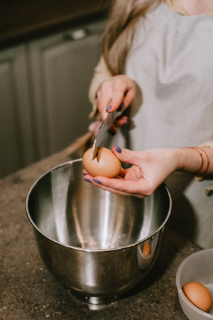 Break an egg into a saucepan. A girl breaks eggs in a bowl to make pastries. The process of baking...