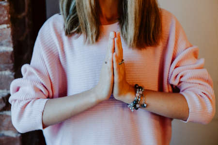 A girl in a pink jacket put her hands together in front of her chest Namaste, greeting in Eastern...