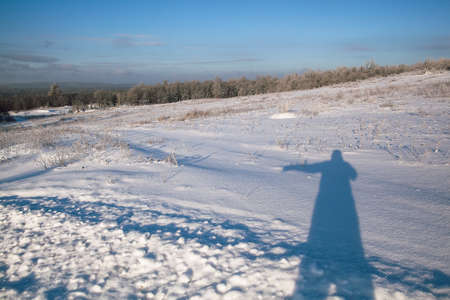 shadow of man in the snow, shadow pattern, cold season, winter out of town, signpost, snow-covered fieldsの写真素材