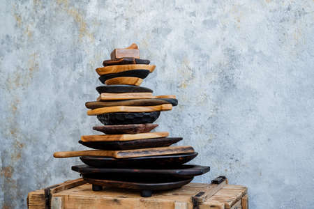 Kitchen utensils made of natural material. The plate lies on the plate, a mountain of wooden plates stands on a chest on a light background. A set of kitchen utensils. High quality photoの写真素材