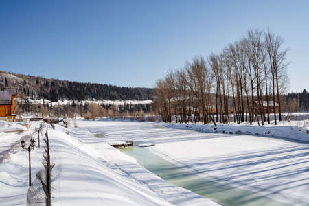 Frozen lake with pier, around large wooden houses and forest. Rest in winter in nature, equipped cottage with access to the water. High quality photoの写真素材
