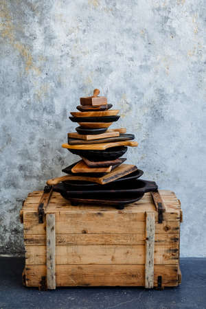 Kitchen utensils made of natural material. The plate lies on the plate, a mountain of wooden plates stands on a chest on a light background. A set of kitchen utensils. High quality photoの写真素材