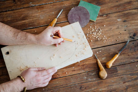 The carpenter draws with a pencil on the board. hand holds a pencil, carpentry workshop, sketch of the future product. High quality photoの写真素材
