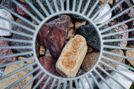Large stones minerals through a lattice with a round hole. Decoration on the street, street...