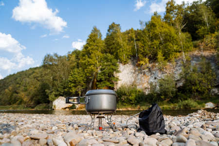 Aluminum pot for cooking on a hike. Cooking on a gas burner on the river bank. Compact lightweight equipment for hiking. High quality photoの写真素材