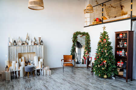 Interior shot. Two-storey room with fireplace, decorated Christmas tree, preparations for the new year Modern apartment. Red staff.High quality photoの写真素材