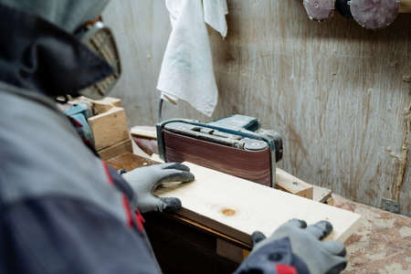 A joiner polishes the board. The process of processing boards in the carpentry workshop. High...