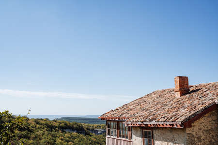 Old house with a tiled roof in the mountains. Clear endless sky, view of the green plains. Rest at...
