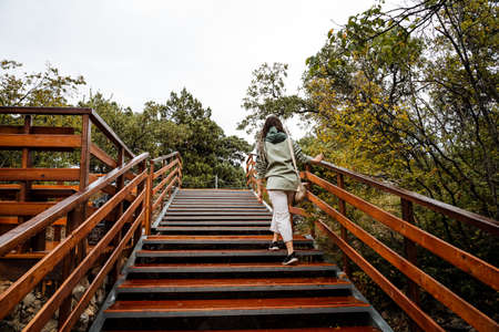 A young girl climbs the stairs. Bright staircase with wide steps. Downhill. Stairs in the park. Walk...