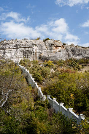 A walled city in the mountains. Ancient historical buildings, a hiking trail for tourists. View of the mountain peaks on a bright sunny dayの写真素材