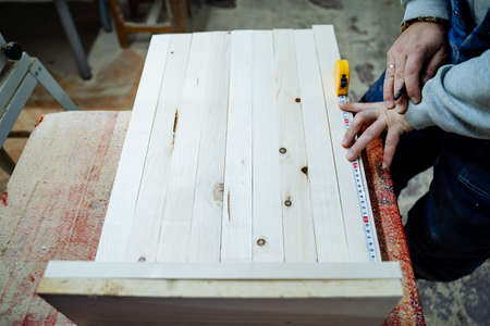 Wood processing. The process of creating wooden furniture. The master takes measurements on the tree. Equipment in the carpentry workshop. High quality photoの写真素材