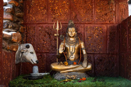 The statue of the bronze Shiva sits in the lotus position. A symbol of the Vedic culture of India. Hindu deity and cow. Place of worship of the god Shivaの写真素材