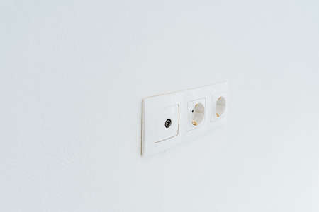 Triple white socket with a switch on the wall. Electricity in the house. Minimalistic interior of a modern house. High quality photoの写真素材