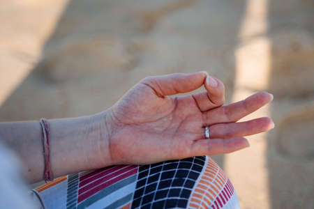 Close shoot of a hand is folded in a meditation pose. Meditation and yoga on the seashore....