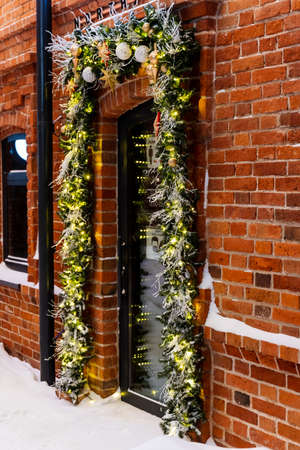 New Year and preparation for the holiday. Christmas decorations at the entrance. A wreath of spruce branches with red, white and gold ornaments. High quality photoの写真素材