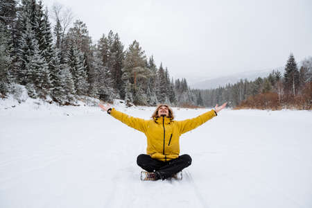 A happy man rejoices in the snowfall. A man sits in the snow. Panoramic view of the forest. A walk in the forest in winter, High quality photoの写真素材