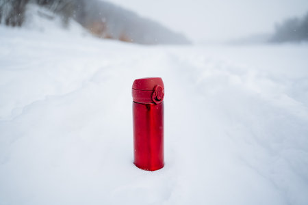A red bottle on the background of snow. Winter photo of mugs. A glass for hot drinks. high quality photoの写真素材