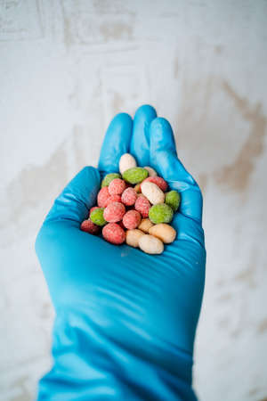 A handful of peanuts colored hand in a glove. Salted nuts are bright in color. The dragee is poured into the hand. Chemical product in a protective glove. high quality photoの写真素材
