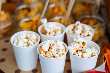 Cups of popcorn with caramel. Crispy sweetness. A bucket of popcorn for a trip to the movies. Five servings of delicious popcorn with caramel. high quality photoの写真素材