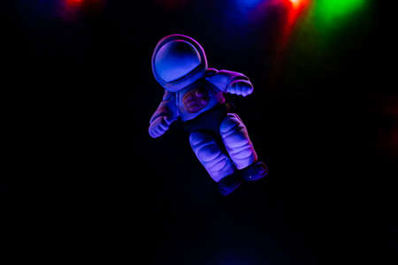 Minimalistic shot of toys, A toy astronaut lies on a dark background. Space flights, toys for children made of plastic and polymer clay. Glare from the garland. high quality photoの写真素材