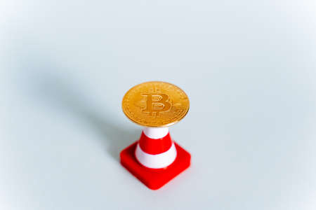 An abstract shot of a bitcoin coin on a white background and a road sign. growing cryptocurrency...