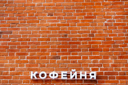 Minimalistic shot of a brick wall with sign. A coffee shop sign on the wall. Announcement on the facade of the building. Red brick masonry. high quality photoの写真素材