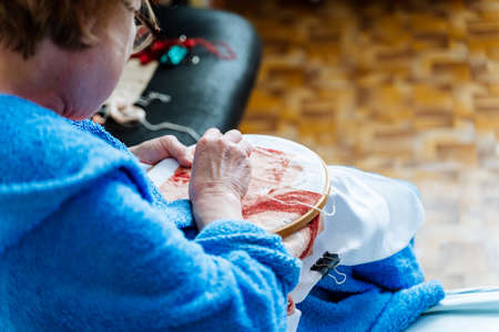 A woman embroiders a pattern on the fabric with her hands. The craft of weaving woolen threads on a...