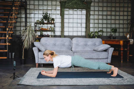 An attractive girl stands in a bar on a yoga mat and looks into the camera.Do yoga at home, stand in...