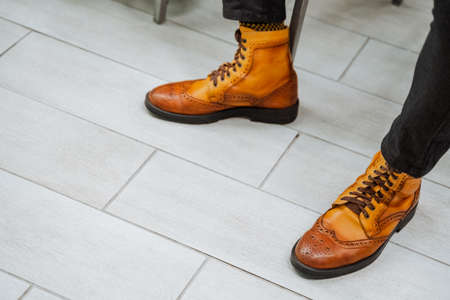 Stylish boots in bright orange. A pair of shoes are worn on their feet. Men's casual style shoes, colorful retro shoes, genuine leather, handmade. high quality photoの写真素材