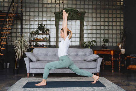A yoga instructor practices at home.A beautiful girl stands in the pose of a good warrior...