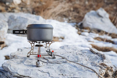 Hiking utensils cooking on a hike gas burner pot for soup, boiling tea on fire, ultra-light gear, mountain climbing, forest survival. high quality photoの写真素材