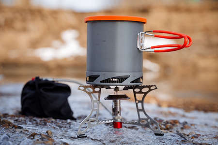 The pot stands on a gas burner against the background of the forest, the dishes hike are shot close-up, a pan with a radiator for heat, an energy condenser, an ultra light bowler gear.の写真素材