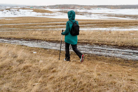 Cardio heart training during Nordic walking, spring hiking on the grass with sticks, a girl in a...