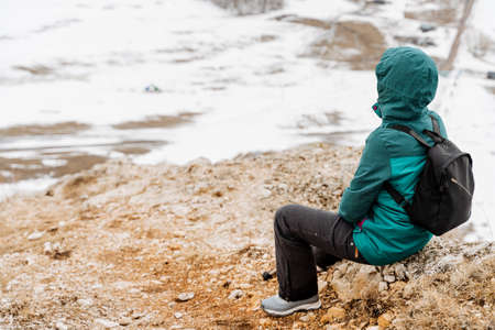 The girl sits on a stone looking into the distance, the view of a man from behind, a tourist...