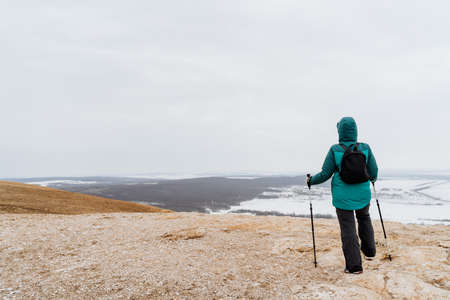 A man stands on top of the mountain Toratau Bashkortostan Russia Southern Urals, Nordic walking with sticks, spring hiking in the mountains, a beautiful view of the valley, a backpack on his backの写真素材