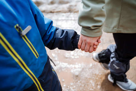 The child holds his mother's hand walking in nature, hands close-up, firmly holding hands, family...