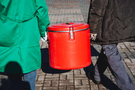 People carry a plastic airtight container, a red vacuum food container, a food service, dangerous cargo, and food delivery. high quality photoの写真素材