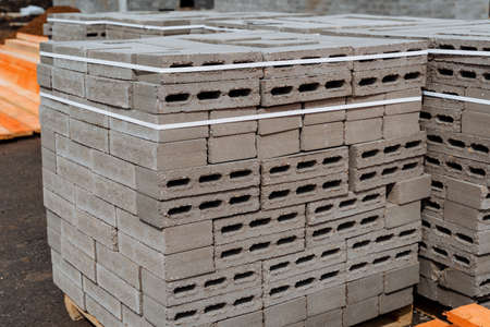 Cinder blocks are packed in even squares tightened with tape, concrete blocks, storage of bricks on the street, building materials made of cement. high quality photoの写真素材