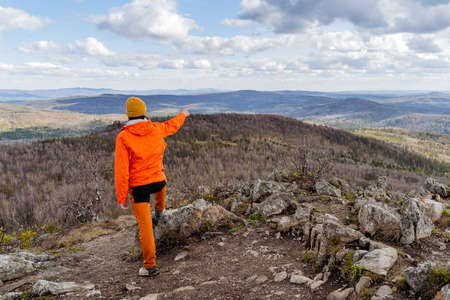 A tourist on a hike points his hand to the top of a mountain, a climber climbed the peak of the...