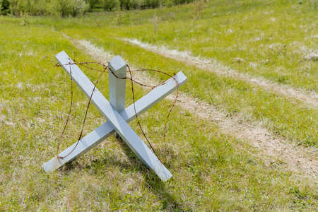 An anti-tank hedgehog, barbed wire wound on a wooden cross, an anti-personnel barrier, a military obstacle. high quality photoの写真素材