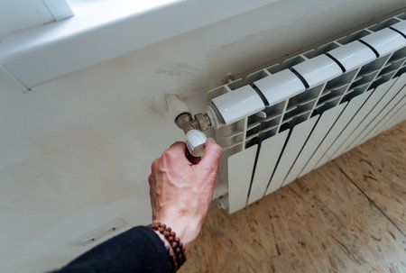 The hand adjusts the temperature level in the radiator, the faucet reduces the heat in the house, smooth adjustment of the power of the water flow into the pipes. home heat exchanger.の写真素材