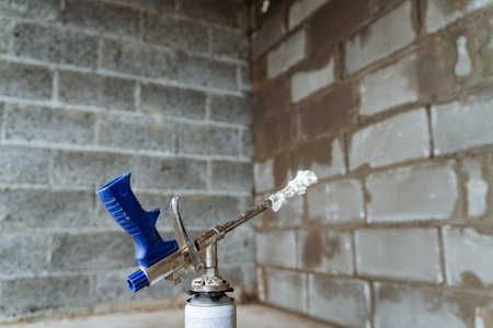 Construction gun emits spray foam, indoor construction, compressed air tool, steel foam tube. high quality photoの写真素材