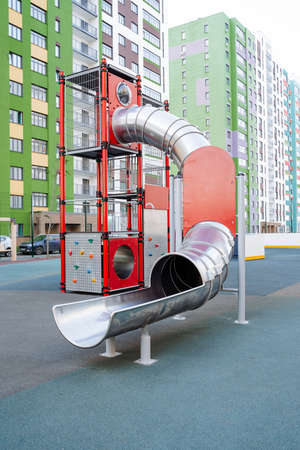 Modern children's playground in the residential complex, metal round tube slide, climber for children. high quality photoの写真素材