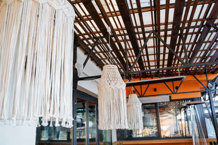 Modern interior design of an outdoor restaurant, a chandelier woven from ropes, fabrics cord hand...