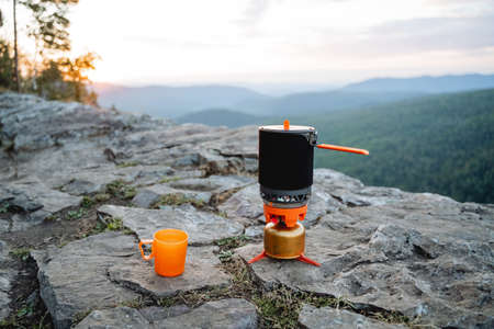 An evening of tranquility in the mountains with a mug of strong tea at sunset. Camping on the...
