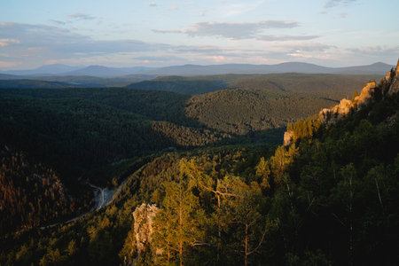 A beautiful landscape of mountains at sunset, the sun illuminates the tops of the trees, the...