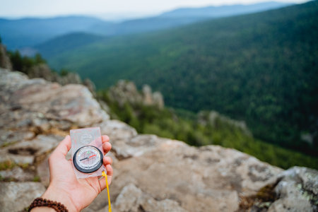orienteering, compass in the hand, mountainous terrain, search for a route in a hike, direction of movement along the azimuth. high quality photoの写真素材