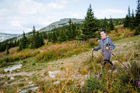 Mountain travel, beautiful girl walking in hiking, mountain trekking, outdoor vacation, outdoor activities, mountain climbing, walking poles. High quality photoの写真素材