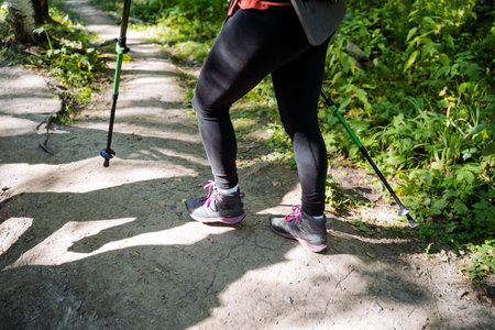 Norwegian walking with poles in the forest, mountain boots, trekking shoes for serious climbing in the mountains, womens legs in leggings, hiking.の写真素材